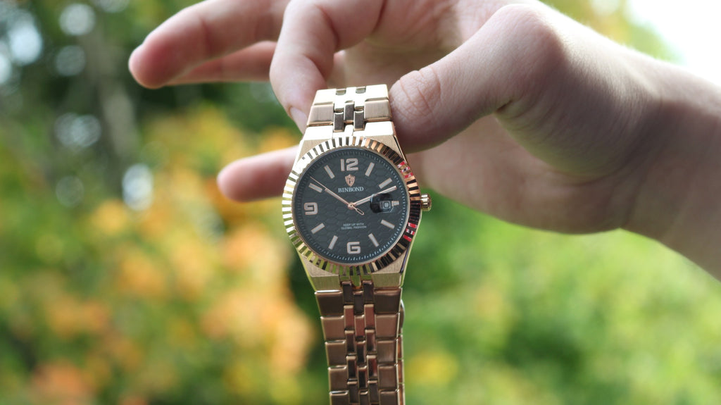 Bartlett 1954 Coralis in rose gold held up outdoors, black honeycomb dial and fluted bezel