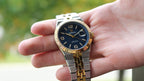 Bartlett 1954 Coralis in two-tone with a blue dial held in an open hand outdoors
